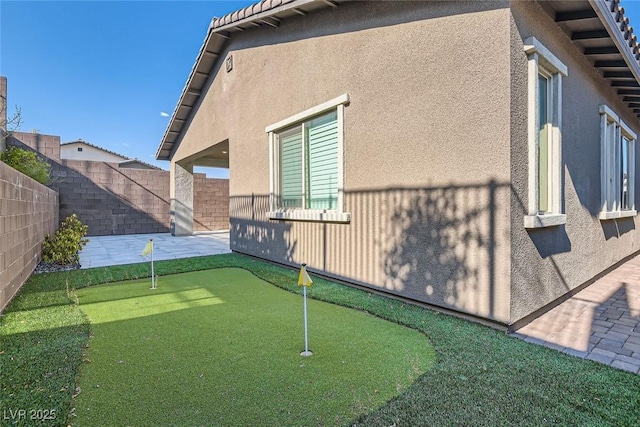 157 Sarabeth St, Las Vegas, NV 89138 - view of property exterior featuring a putting area, stucco siding, a patio, and a fenced backyard