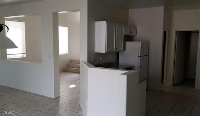 3644 Starlight Evening St, Las Vegas, NV 89129 - kitchen with light tile patterned floors, freestanding refrigerator, a peninsula, and white cabinets