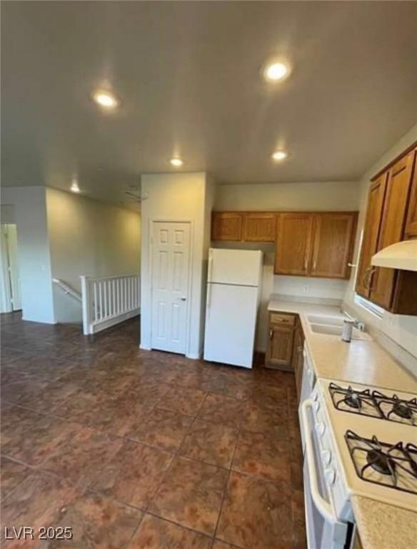 9402 Crimson Sky St, Las Vegas, NV 89178 - kitchen with white appliances, under cabinet range hood, light countertops, recessed lighting, and brown cabinets