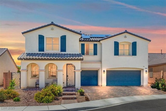 8925 Kenzie Cove St, Las Vegas, NV 89131 - mediterranean / spanish house with an attached garage, stucco siding, roof mounted solar panels, covered porch, and a tile roof