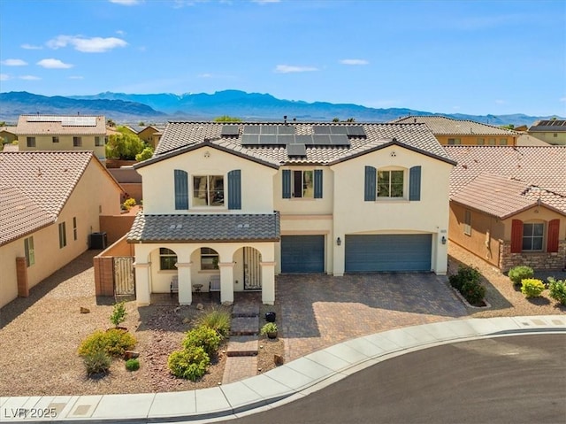 8925 Kenzie Cove St, Las Vegas, NV 89131 - mediterranean / spanish home featuring a mountain view, stucco siding, covered porch, an attached garage, and roof mounted solar panels