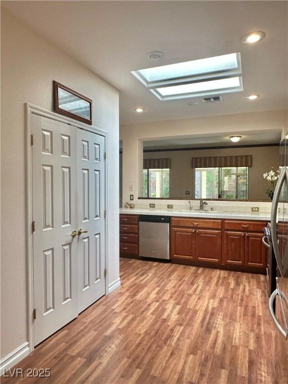 2138 Grand Traverse St, Henderson, NV 89052 - kitchen with stainless steel dishwasher, a skylight, light wood-style floors, a sink, and recessed lighting