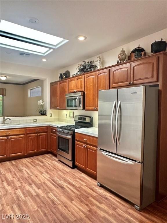 2138 Grand Traverse St, Henderson, NV 89052 - kitchen featuring appliances with stainless steel finishes, a sink, light wood-style floors, brown cabinets, and recessed lighting