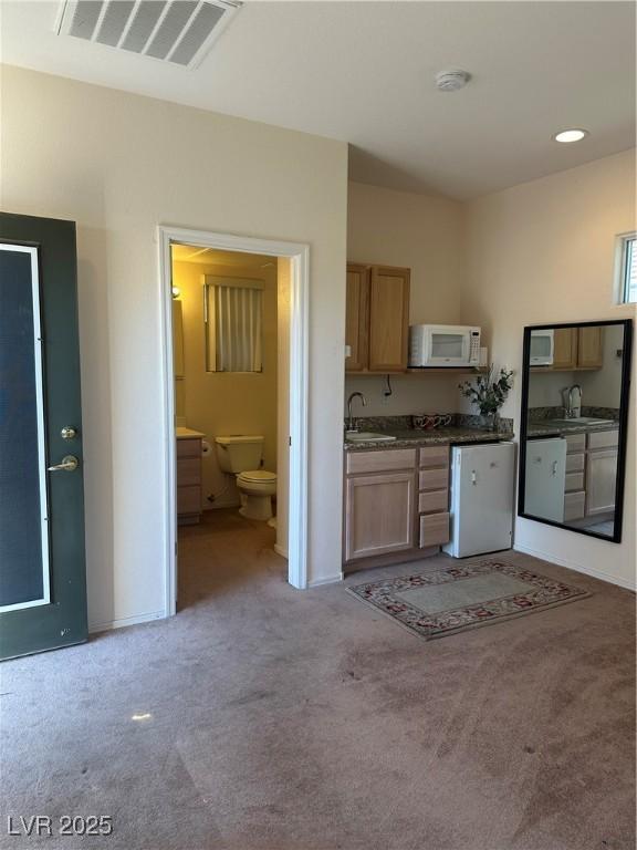 2138 Grand Traverse St, Henderson, NV 89052 - kitchen with white microwave, light carpet, a sink, and baseboards