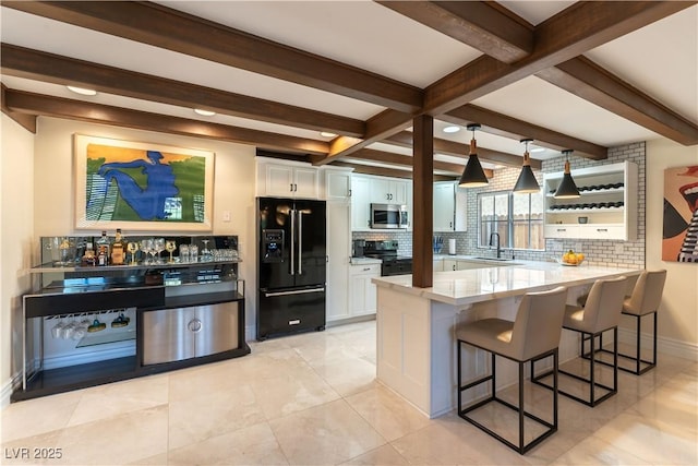 2845 Queens Courtyard Dr, Las Vegas, NV 89109 - kitchen featuring black appliances, backsplash, white cabinetry, beamed ceiling, and a peninsula