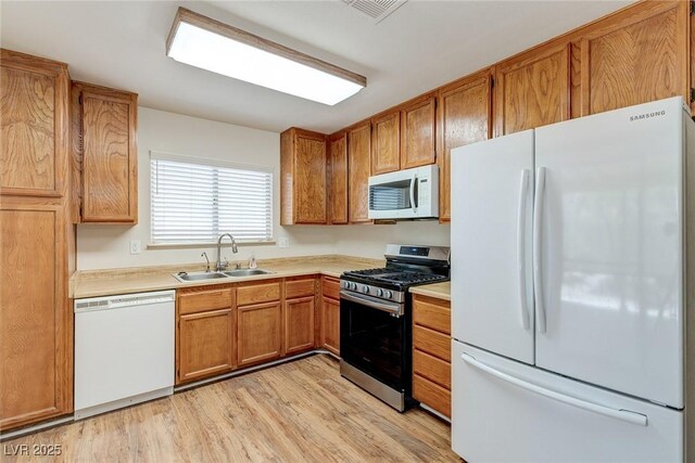 4916 Carmichael Ave, Las Vegas, NV 89110 - kitchen featuring white appliances, a sink, light countertops, brown cabinetry, and light wood-style flooring