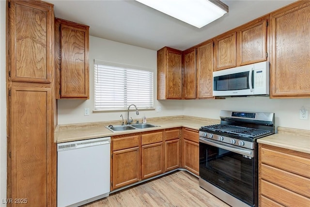 4916 Carmichael Ave, Las Vegas, NV 89110 - kitchen with white appliances, a sink, light countertops, brown cabinets, and light wood-style floors