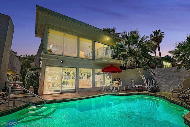 940 Vegas Valley Dr, Las Vegas, NV 89109 - back of house at dusk featuring a balcony, an outdoor pool, and a patio