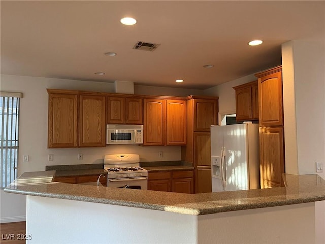 5049 Alfingo St, Las Vegas, NV 89135 - kitchen with white appliances, recessed lighting, brown cabinetry, and a peninsula