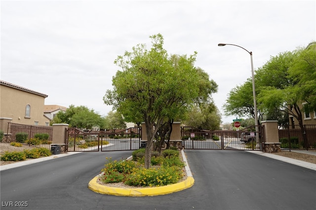 9312 Poseidon Valley Ave, Las Vegas, NV 89178 - view of asphalt road featuring a gate, curbs, a gated entry, and traffic signs