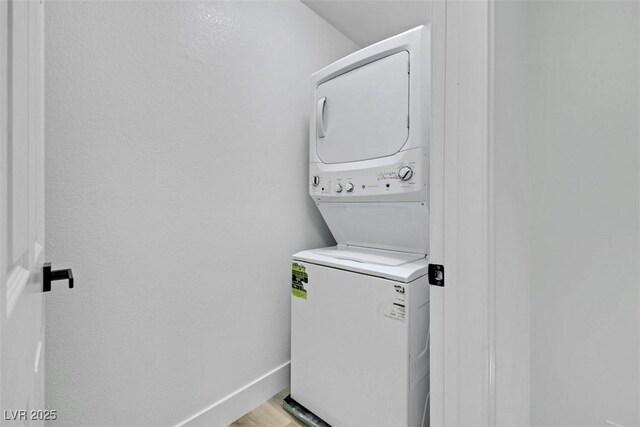 9078 Hilverson Ave, Las Vegas, NV 89148 - washroom featuring stacked washer and clothes dryer, baseboards, and light wood-style floors