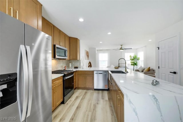 9078 Hilverson Ave, Las Vegas, NV 89148 - kitchen featuring appliances with stainless steel finishes, a sink, brown cabinets, light wood finished floors, and light stone counters