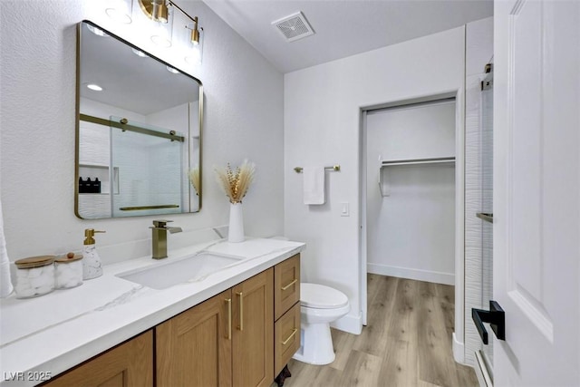 9078 Hilverson Ave, Las Vegas, NV 89148 - full bath featuring toilet, vanity, a shower with door, wood finished floors, and a walk in closet