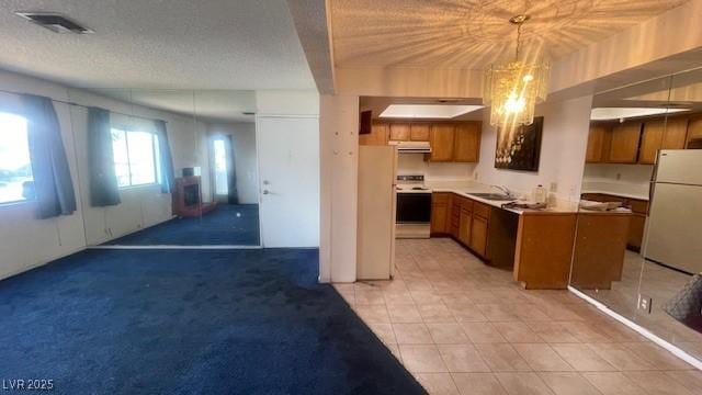 1701 E Katie Ave Unit 91, Las Vegas, NV 89119 - kitchen with white appliances, brown cabinetry, open floor plan, a sink, and hanging light fixtures