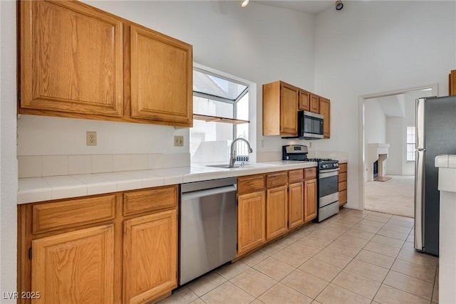 2904 Channel Bay Dr, Las Vegas, NV 89128 - kitchen with stainless steel appliances, a towering ceiling, light tile patterned floors, light countertops, and light colored carpet