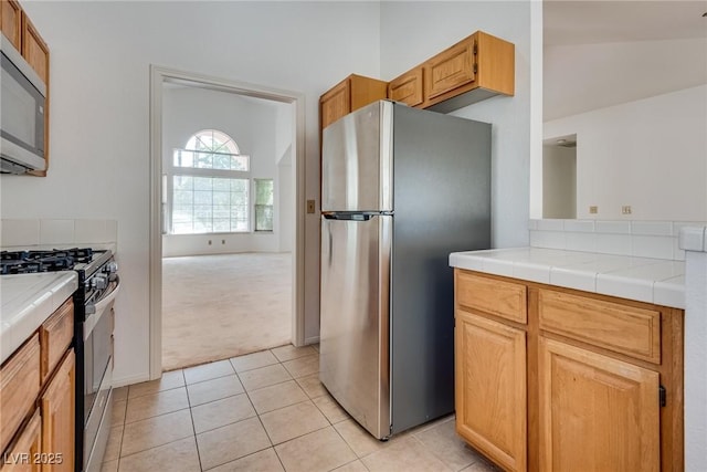2904 Channel Bay Dr, Las Vegas, NV 89128 - kitchen with appliances with stainless steel finishes, tile counters, light carpet, light tile patterned flooring, and lofted ceiling