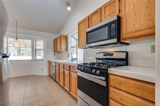 2904 Channel Bay Dr, Las Vegas, NV 89128 - kitchen with stainless steel appliances, vaulted ceiling, light tile patterned flooring, tile countertops, and pendant lighting