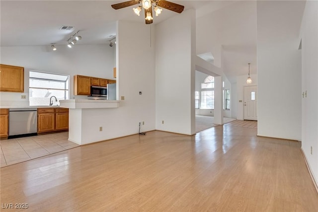 2904 Channel Bay Dr, Las Vegas, NV 89128 - unfurnished living room featuring high vaulted ceiling, healthy amount of natural light, a ceiling fan, light wood-type flooring, and track lighting