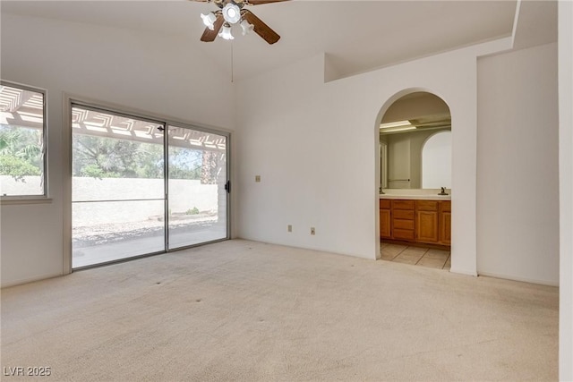 2904 Channel Bay Dr, Las Vegas, NV 89128 - empty room with light carpet, healthy amount of natural light, a ceiling fan, arched walkways, and lofted ceiling