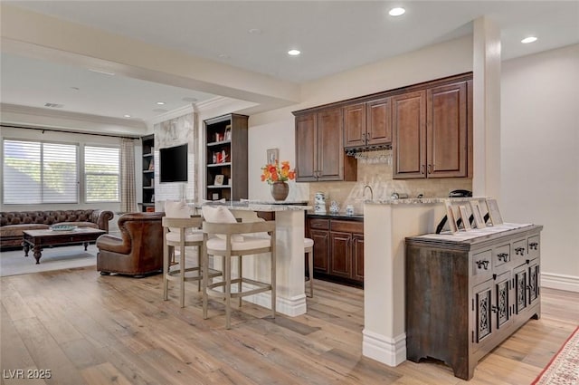 748 Puerto Real Ct, Las Vegas, NV 89138 - kitchen with a kitchen breakfast bar, open floor plan, light wood-style flooring, ornamental molding, and recessed lighting