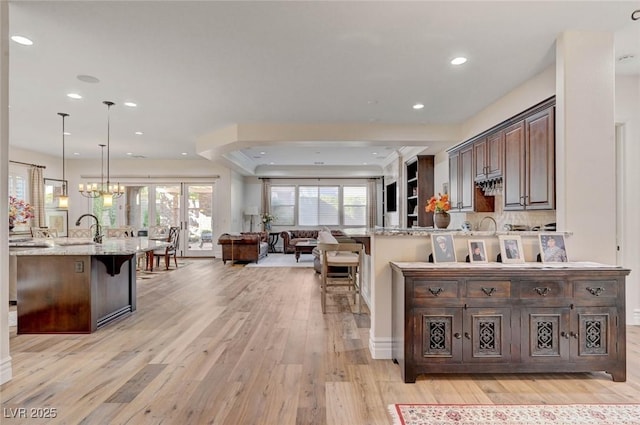 748 Puerto Real Ct, Las Vegas, NV 89138 - kitchen featuring a kitchen breakfast bar, open floor plan, light wood-type flooring, light stone counters, and recessed lighting
