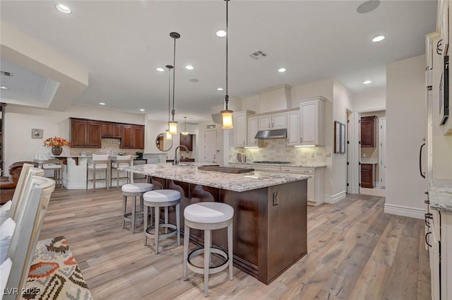 748 Puerto Real Ct, Las Vegas, NV 89138 - kitchen featuring light wood-style floors, tasteful backsplash, a sink, under cabinet range hood, and recessed lighting