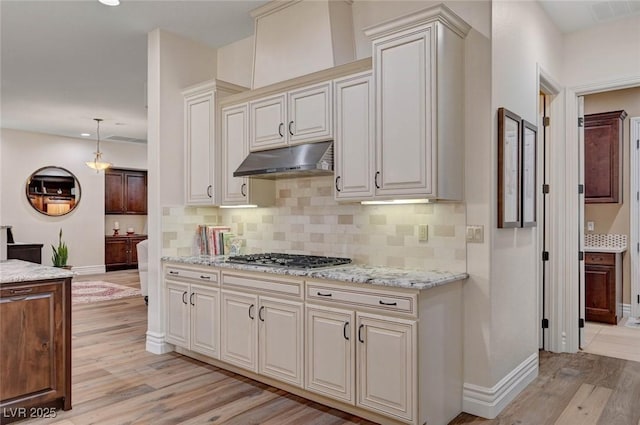 748 Puerto Real Ct, Las Vegas, NV 89138 - kitchen featuring stainless steel gas cooktop, under cabinet range hood, light wood-type flooring, baseboards, and backsplash