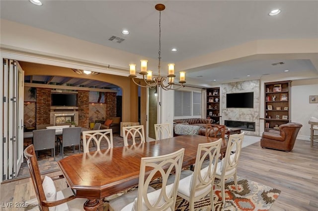 748 Puerto Real Ct, Las Vegas, NV 89138 - dining space featuring a high end fireplace, built in shelves, a chandelier, light wood-style flooring, and recessed lighting
