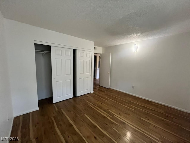 3585 Arville St Unit 403A, Las Vegas, NV 89103 - unfurnished bedroom with dark wood-type flooring, a closet, baseboards, and a textured ceiling