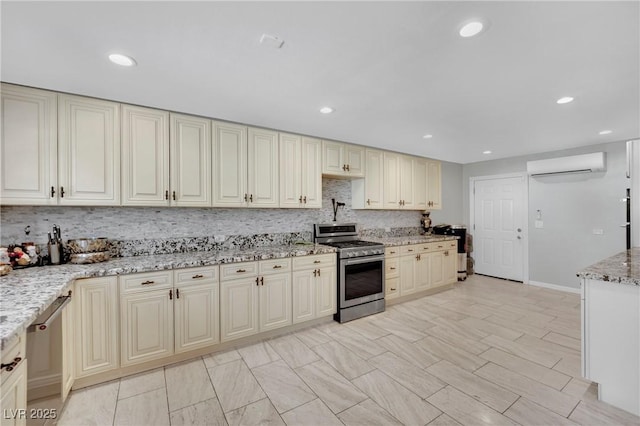2131 Diamond Bar Dr, Las Vegas, NV 89117 - kitchen with appliances with stainless steel finishes, a wall mounted air conditioner, cream cabinets, light stone counters, and tasteful backsplash