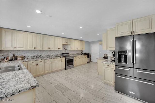 2131 Diamond Bar Dr, Las Vegas, NV 89117 - kitchen with appliances with stainless steel finishes, cream cabinetry, backsplash, light stone countertops, and recessed lighting