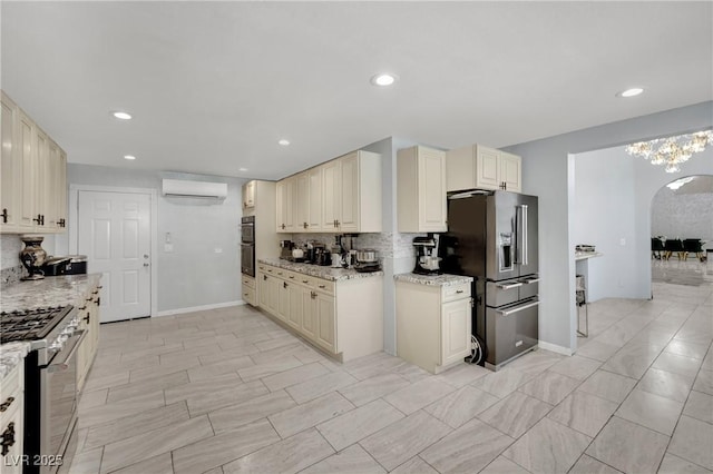 2131 Diamond Bar Dr, Las Vegas, NV 89117 - kitchen featuring stainless steel appliances, a wall mounted air conditioner, cream cabinetry, decorative backsplash, and arched walkways