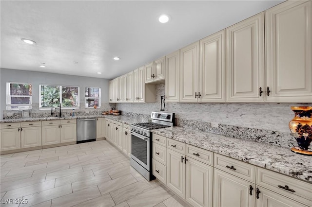 2131 Diamond Bar Dr, Las Vegas, NV 89117 - kitchen featuring stainless steel appliances, a sink, cream cabinetry, tasteful backsplash, and light stone countertops