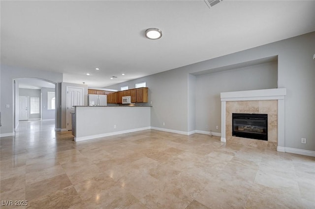 10518 Santerno St, Las Vegas, NV 89141 - unfurnished living room with arched walkways, a tiled fireplace, recessed lighting, and baseboards