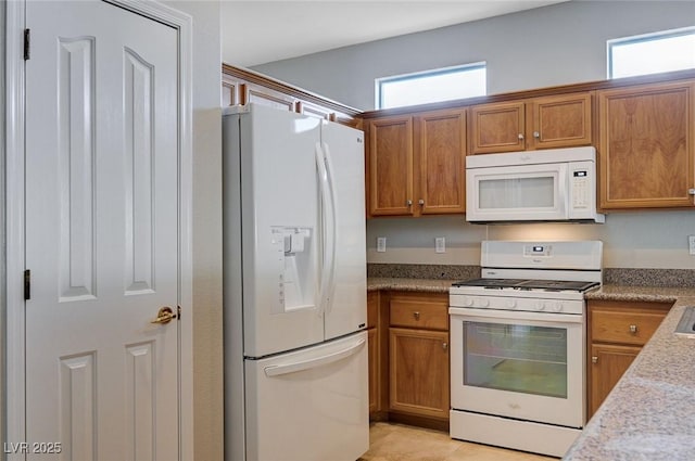 10518 Santerno St, Las Vegas, NV 89141 - kitchen with white appliances, brown cabinetry, and light stone countertops
