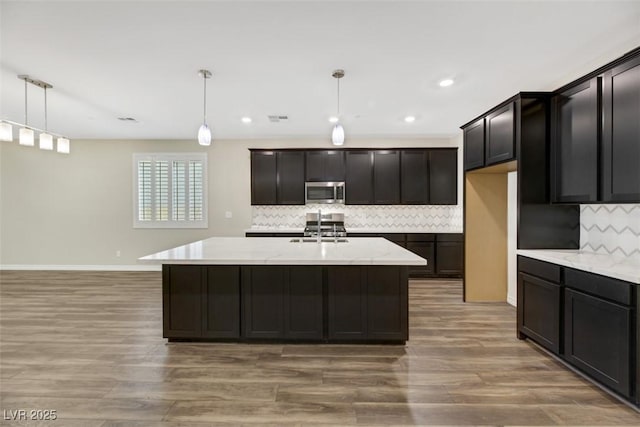 234 Polaris Ridge Ave, Henderson, NV 89011 - kitchen featuring appliances with stainless steel finishes, light wood finished floors, tasteful backsplash, pendant lighting, and recessed lighting