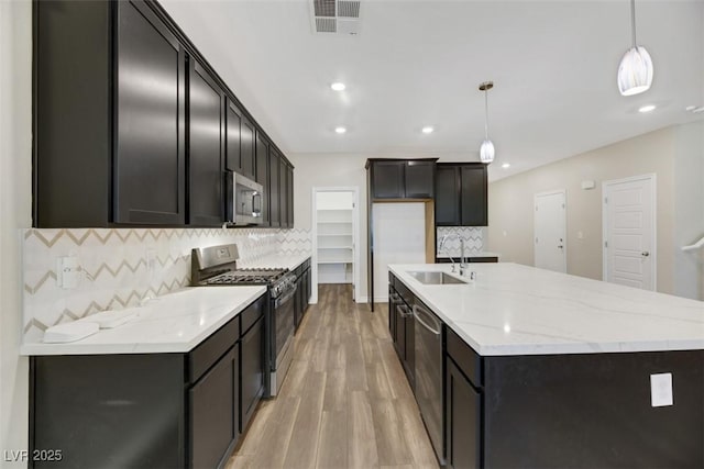 234 Polaris Ridge Ave, Henderson, NV 89011 - kitchen with stainless steel appliances, a sink, light wood-type flooring, decorative backsplash, and a spacious island