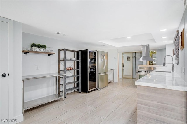945 Vegas Valley Dr, Las Vegas, NV 89109 - kitchen featuring a sink, island range hood, a tray ceiling, light stone counters, and stainless steel range oven