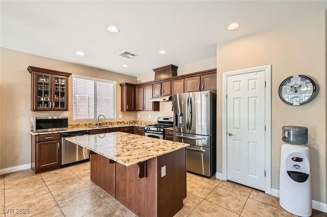 10121 Iron Wood Peak Ave, Las Vegas, NV 89166 - kitchen featuring stainless steel appliances, under cabinet range hood, a sink, a kitchen island, and light stone countertops