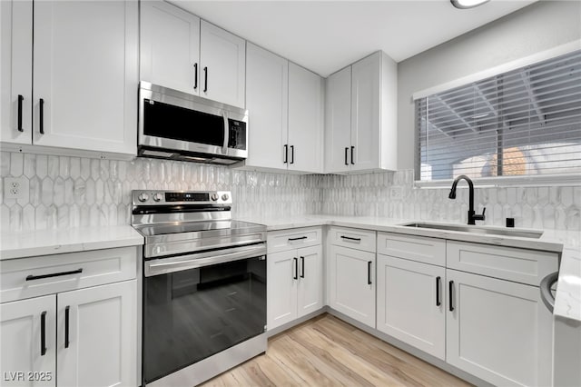 5453 Yvonne Cir, Las Vegas, NV 89122 - kitchen with appliances with stainless steel finishes, white cabinets, light wood-type flooring, decorative backsplash, and light stone counters