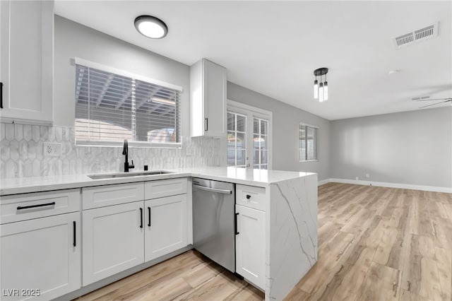 5453 Yvonne Cir, Las Vegas, NV 89122 - kitchen with stainless steel dishwasher, a peninsula, open floor plan, backsplash, and white cabinetry