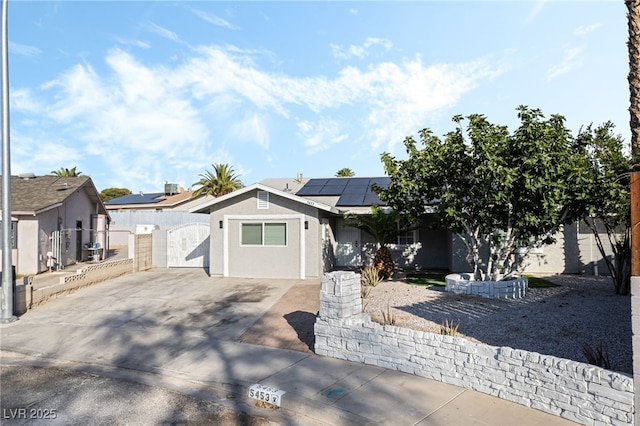5453 Yvonne Cir, Las Vegas, NV 89122 - view of front facade featuring a gate, roof mounted solar panels, stucco siding, and concrete driveway
