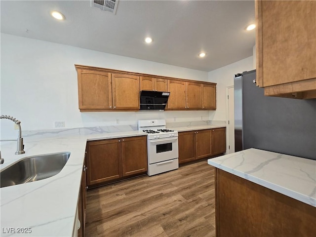 6638 Babys Tear Pl, Las Vegas, NV 89148 - kitchen featuring gas range gas stove, a sink, black microwave, freestanding refrigerator, and wood finished floors
