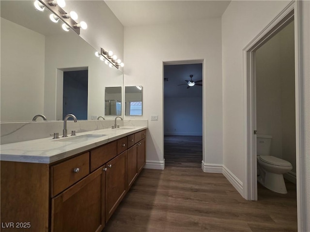 6638 Babys Tear Pl, Las Vegas, NV 89148 - full bath with double vanity, wood finished floors, toilet, baseboards, and a ceiling fan