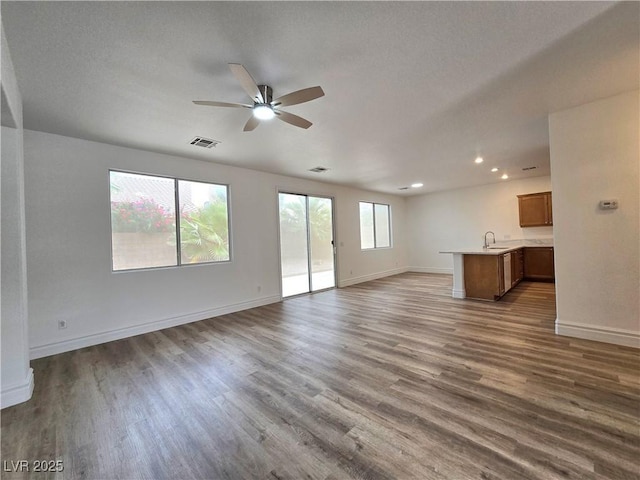 6638 Babys Tear Pl, Las Vegas, NV 89148 - unfurnished living room with wood finished floors, ceiling fan, baseboards, recessed lighting, and a sink