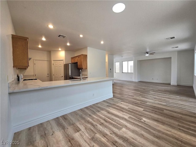 6638 Babys Tear Pl, Las Vegas, NV 89148 - kitchen with freestanding refrigerator, brown cabinets, baseboards, wood finished floors, and recessed lighting