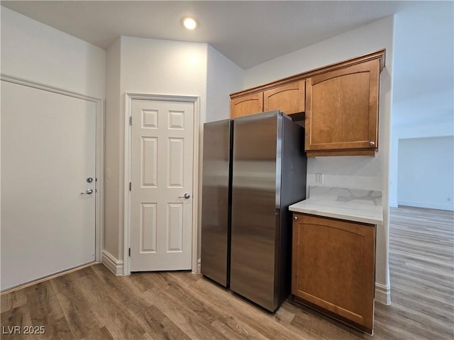 6638 Babys Tear Pl, Las Vegas, NV 89148 - kitchen featuring freestanding refrigerator, light wood-style floors, brown cabinetry, recessed lighting, and baseboards
