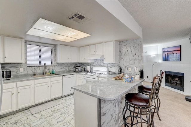 6735 W Charleston Blvd Unit 4, Las Vegas, NV 89146 - kitchen with a sink, white appliances, a peninsula, white cabinets, and a kitchen bar