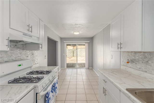 2432 Spanish Ct, Las Vegas, NV 89108 - kitchen featuring white gas range, under cabinet range hood, light tile patterned flooring, white cabinetry, and a textured ceiling