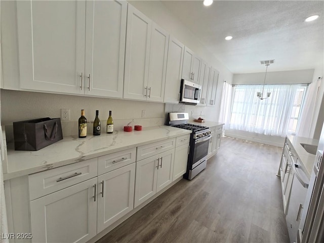 8545 Summer Vista Ave, Las Vegas, NV 89145 - kitchen with appliances with stainless steel finishes, recessed lighting, wood finished floors, white cabinets, and decorative light fixtures